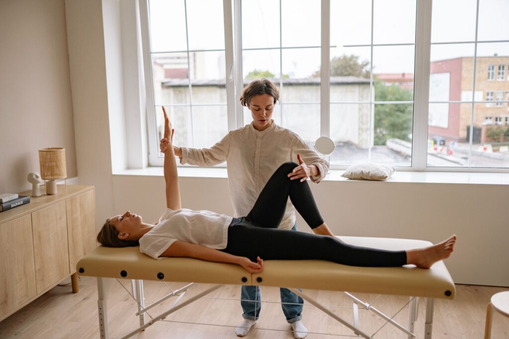 A specialist performs therapy on a woman lying on a massage table in a modern clinic setting, physical therapy hampton ga